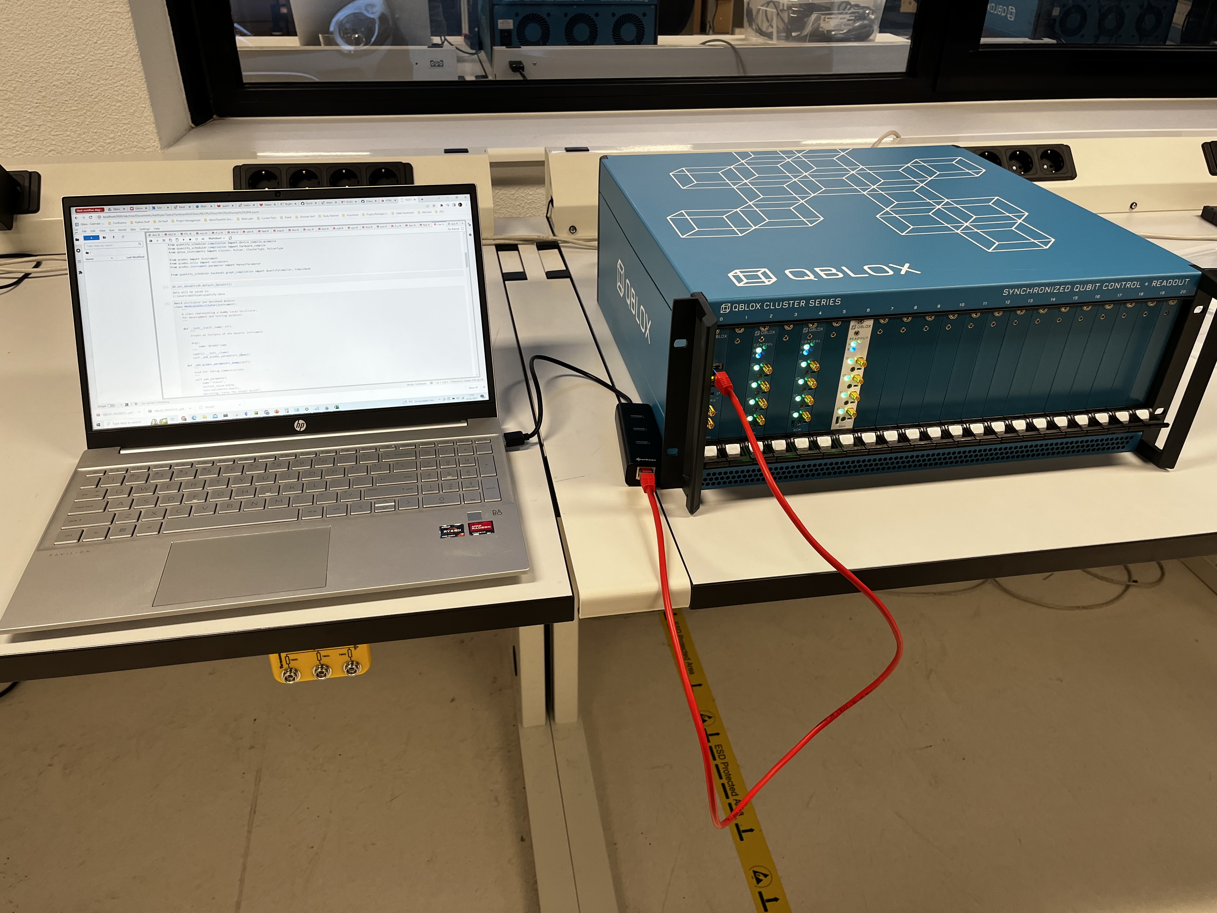 A Qblox Cluster connected to a laptop using a USB Ethernet adapter.
